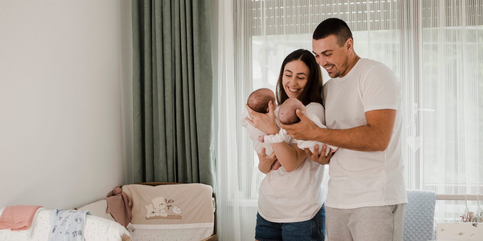 Young married couple with newborn twins enjoying family time in the morning